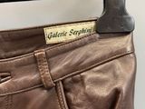 the back of a pair of brown leather pants hanging on a hanger