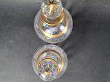 two clear glass jars with gold trims on a table