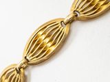 a close up of a gold plated bracelet on a white surface