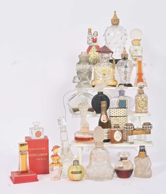 plusieurs flacons de parfum posés sur une étagère, à côté d'un livre