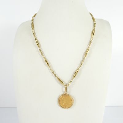 un gros plan d'un collier orné d'une pièce de monnaie, porté par un mannequin