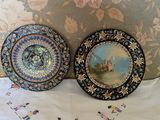 two decorative plates sitting on a bed with a floral wallpaper