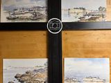 four paintings on the wall of a room with a camera