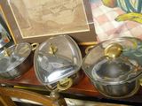 trois casseroles et poêles posées sur une table à côté d'un tableau