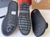 two pairs of black shoes with black soles on a white surface
