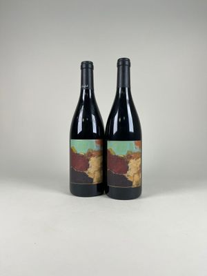 two bottles of red wine sitting next to each other on a table
