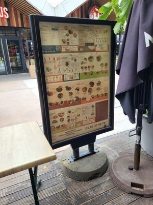 un panneau présentant le menu, posé sur la table à l'extérieur d'un restaurant