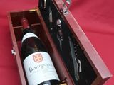a bottle of wine in a wooden case on a red cloth