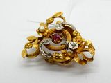 a gold brooch with a red stone in it