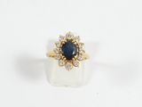 a close up of a blue sapphire and diamond ring on a white surface
