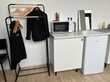 une petite cuisine équipée d'un micro-ondes, d'un réfrigérateur et d'un étendoir à linge