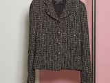 une veste noire et blanche accrochée à un portant près d'un mur rose