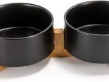 two black bowls with wooden stands on a white surface