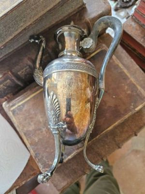 un vase en argent muni d'une anse, posé sur une table