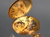 a gold pocket watch sitting on top of a glass table