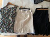 three skirts and a top on a bed next to a pair of shoes