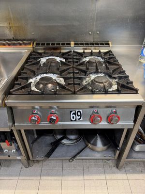 stainless steel stove top with six burners in a commercial kitchen