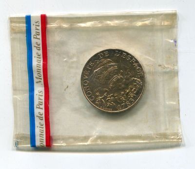 a coin in a clear bag with a red, white, and blue ribbon