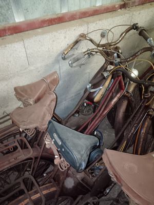 a pile of old bicycles and umbrellas in a room