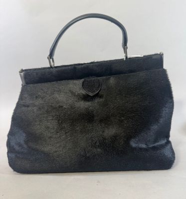 un gros plan d'un sac à main noir posé sur une surface blanche