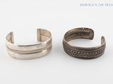 a pair of silver cuff bracelets on a white background