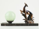 a statue of a bird sitting on a branch next to a lamp