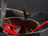 a black bucket with a red handle and a pair of tongs in it