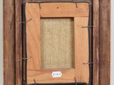 an old picture frame hanging on a wall with a tag on it