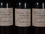 three bottles of red wine are lined up on a shelf