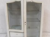 une armoire blanche avec une porte vitrée et des tiroirs