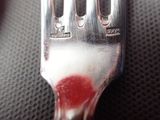 a fork with a red substance on it sitting on a table