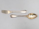 deux cuillères et une fourchette en argent sur une surface blanche