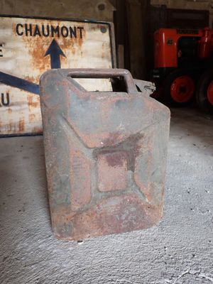 un bidon rouillé posé dans un garage à côté d'un panneau