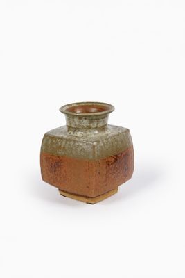 un petit vase posé sur une surface blanche