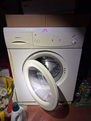 une machine à laver posée par terre à côté d'une poubelle