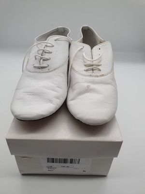 une paire de chaussures blanches posée sur une boîte, elle-même posée sur une surface blanche