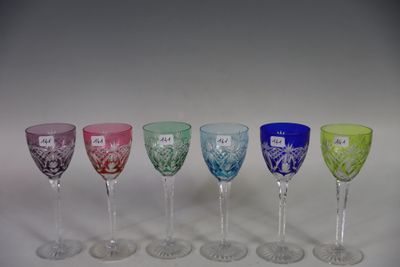 several different colored wine glasses are lined up on a white surface