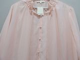 the pink blouse is hanging on a hanger on the wall