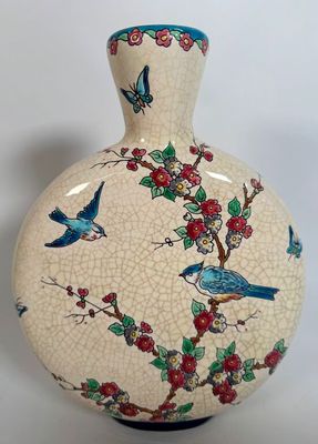 a vase with a bird design on it sitting on a table