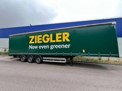 une semi-remorque verte garée devant un immeuble