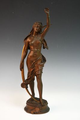 une statue antique en bronze représentant une femme tenant un serpent, posée sur un socle