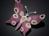 a close up of a pink butterfly broochle on a black surface