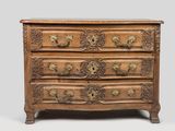 une commode ancienne ornée de sculptures raffinées et dotée de poignées en laiton