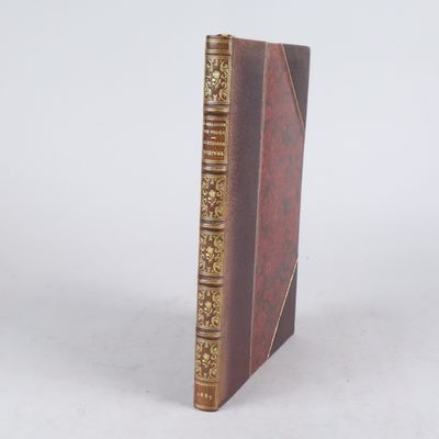 un livre marron aux bords dorés posé sur une surface blanche
