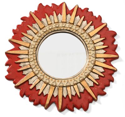 un miroir rouge et doré à rayons de soleil accroché à un mur blanc