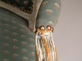 a close up of a chair with a tassel on the arm