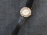 un gros plan d'une montre-bracelet posée sur une surface grise