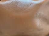 brown leather purse sitting on top of a wooden table next to a window