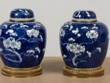 two blue vases with white flowers on them sitting on a table