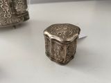 a small silver box sitting on a table next to a smaller silver box